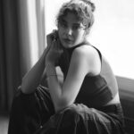 Intimate black and white portrait of a young woman sitting near a window.